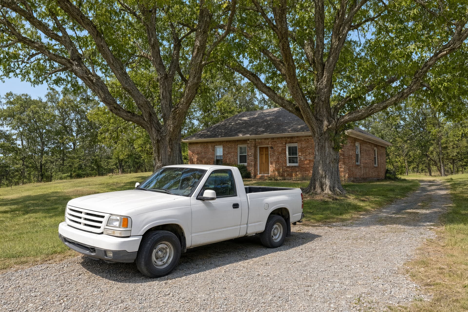 Rural brick home under two big pecan trees with a gravel drive and a white pickup, like the homes around Bono, AR